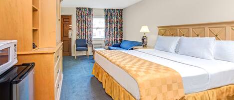A hotel room with a bed, a desk, a microwave, and a chair.