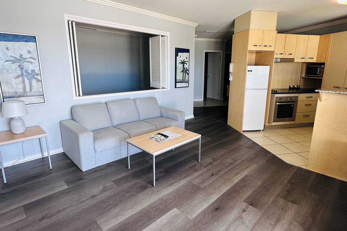 Un salón con sofá, mesa de centro y una ventana con persianas.