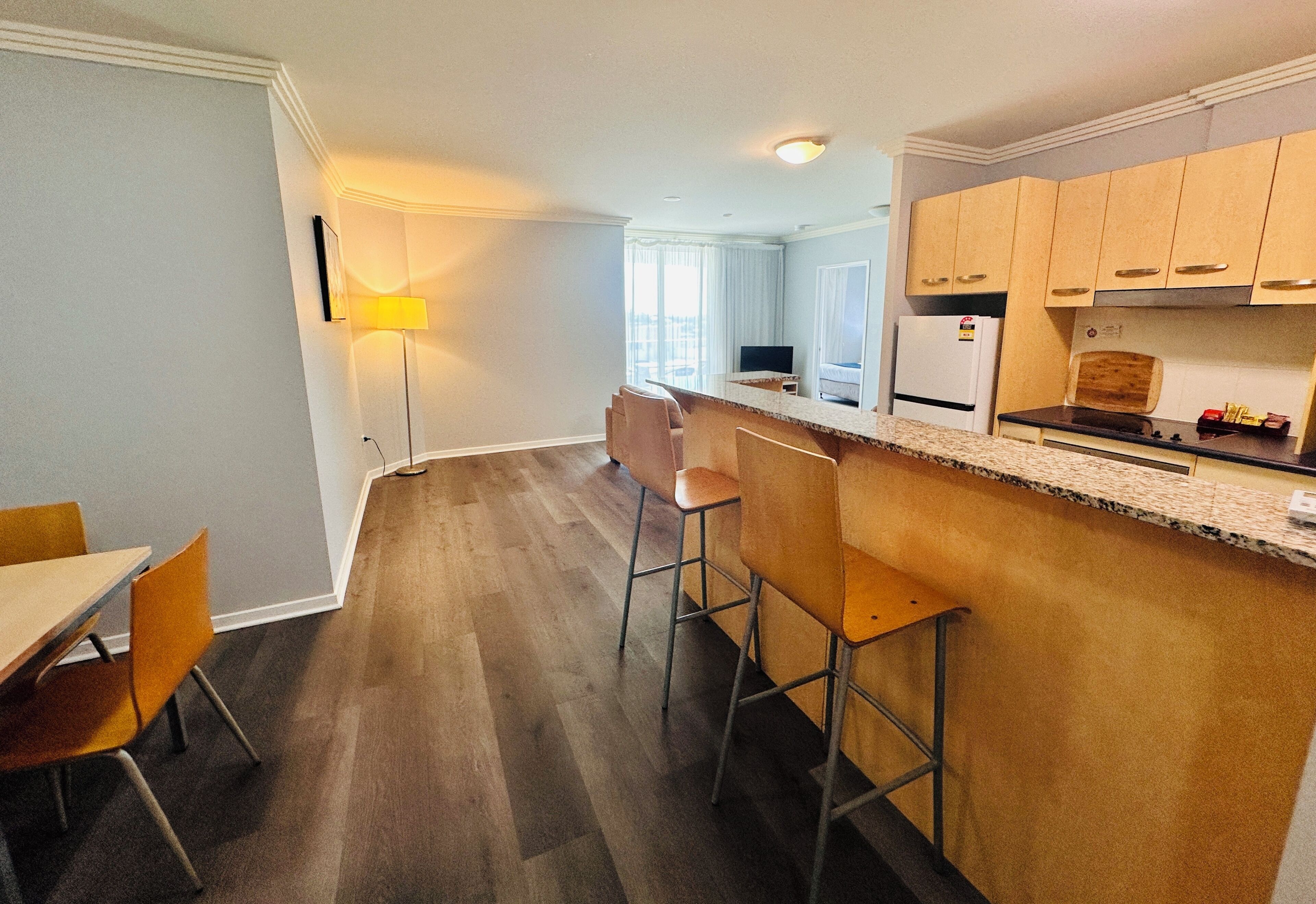 Une cuisine moderne avec un coin bar, un plancher en bois et une table à manger avec des chaises.
