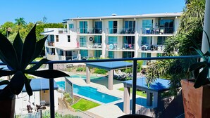 Un hôtel à plusieurs étages doté d’une piscine, de balcons et d’un espace extérieur aménagé pour s’asseoir.