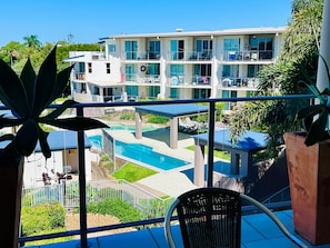 A multi-story hotel with a pool, balconies, and outdoor seating.