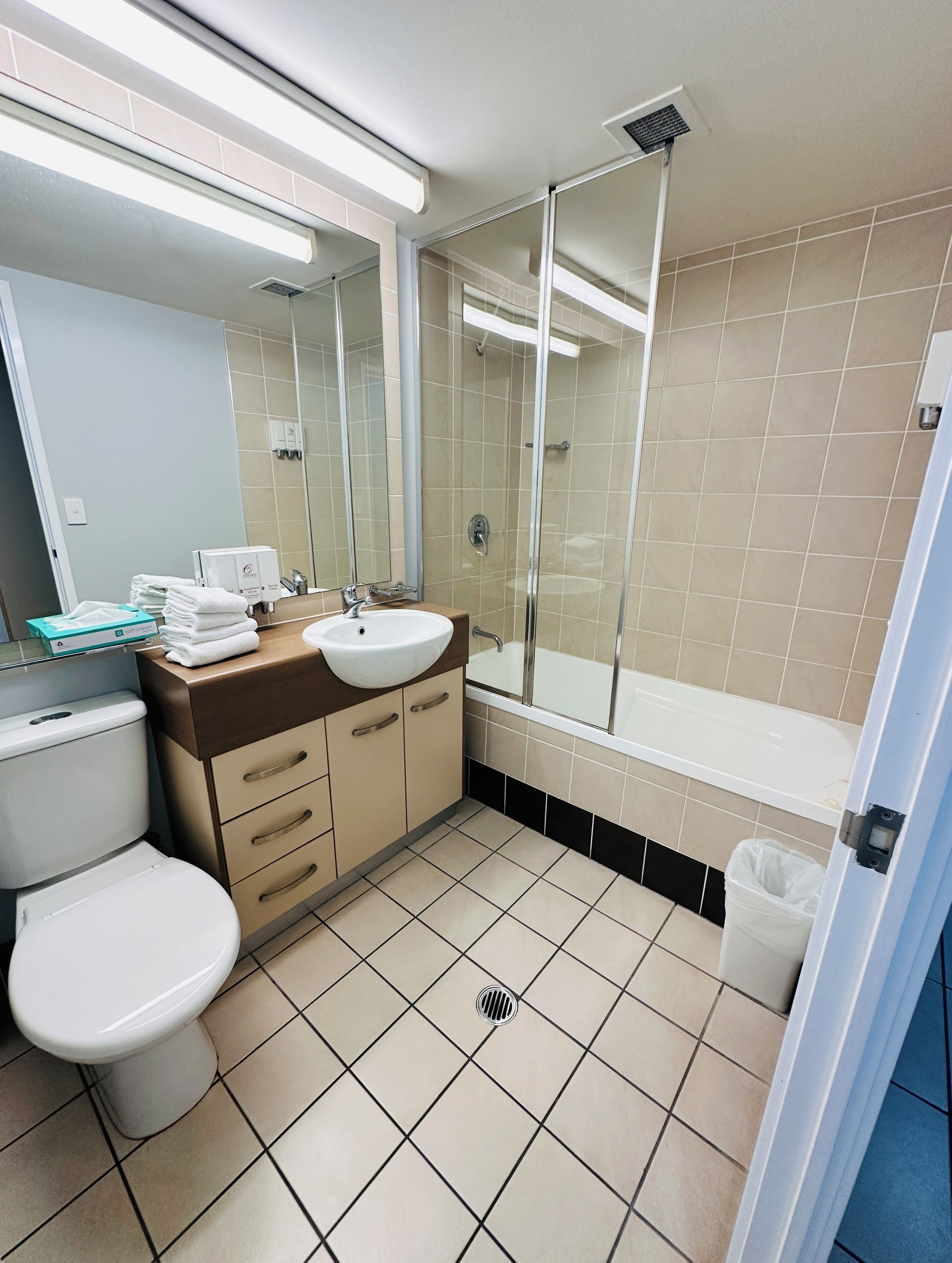 Un baño con inodoro, lavamanos, espejo, ducha y suelo de baldosas.