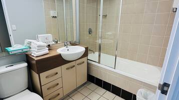 Een badkamer met toilet, wastafel, spiegel, douche en betegelde vloer.
