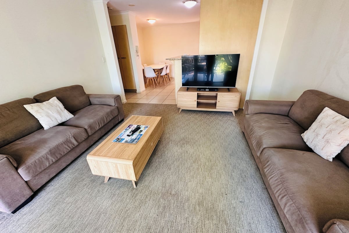 Una sala de estar con dos sofás, una mesa de centro y un mueble para televisión.