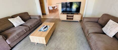 A living room with two sofas, a coffee table, and a TV stand.