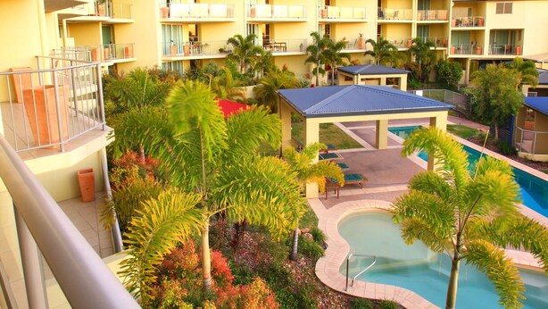 Un hôtel doté de nombreux balcons, d’une piscine et d’un aménagement paysager luxuriant.