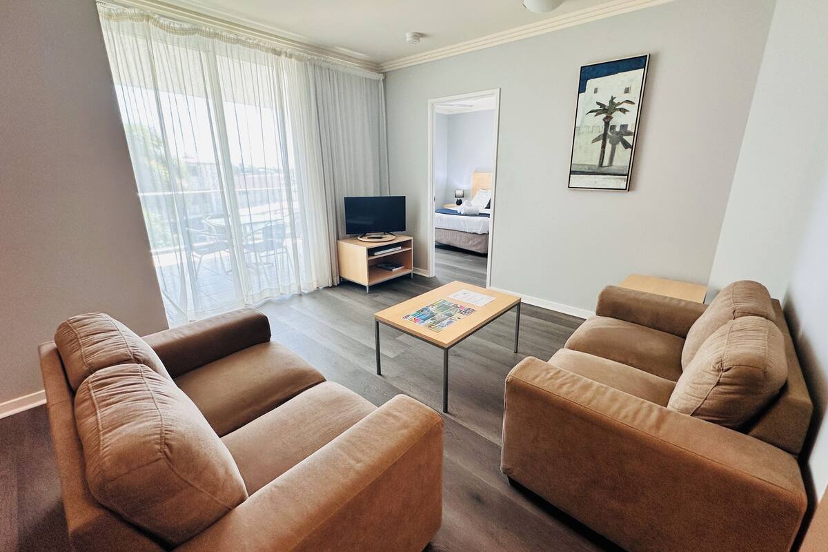 Una sala de estar con dos sofás, una mesa de centro, un televisor y un cuadro en la pared.