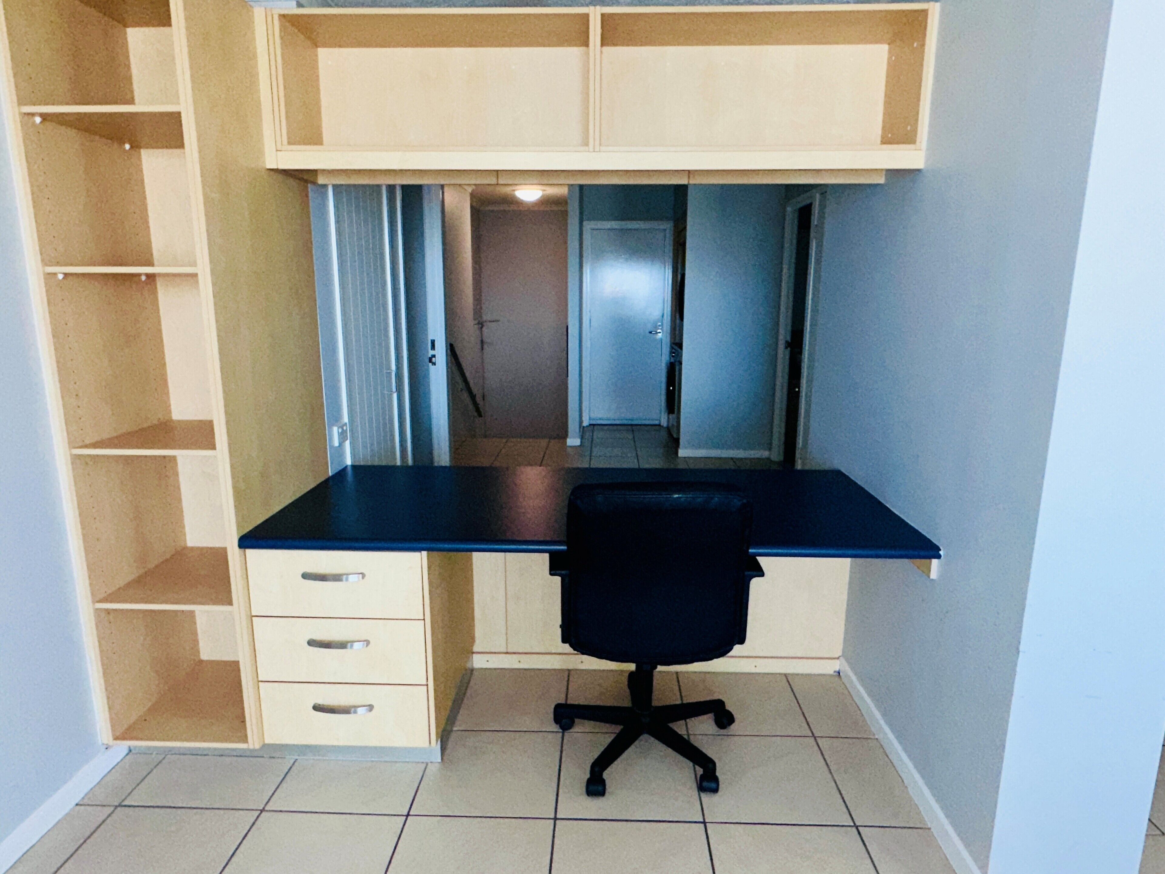 A compact office space with a desk, chair, and built-in shelving.