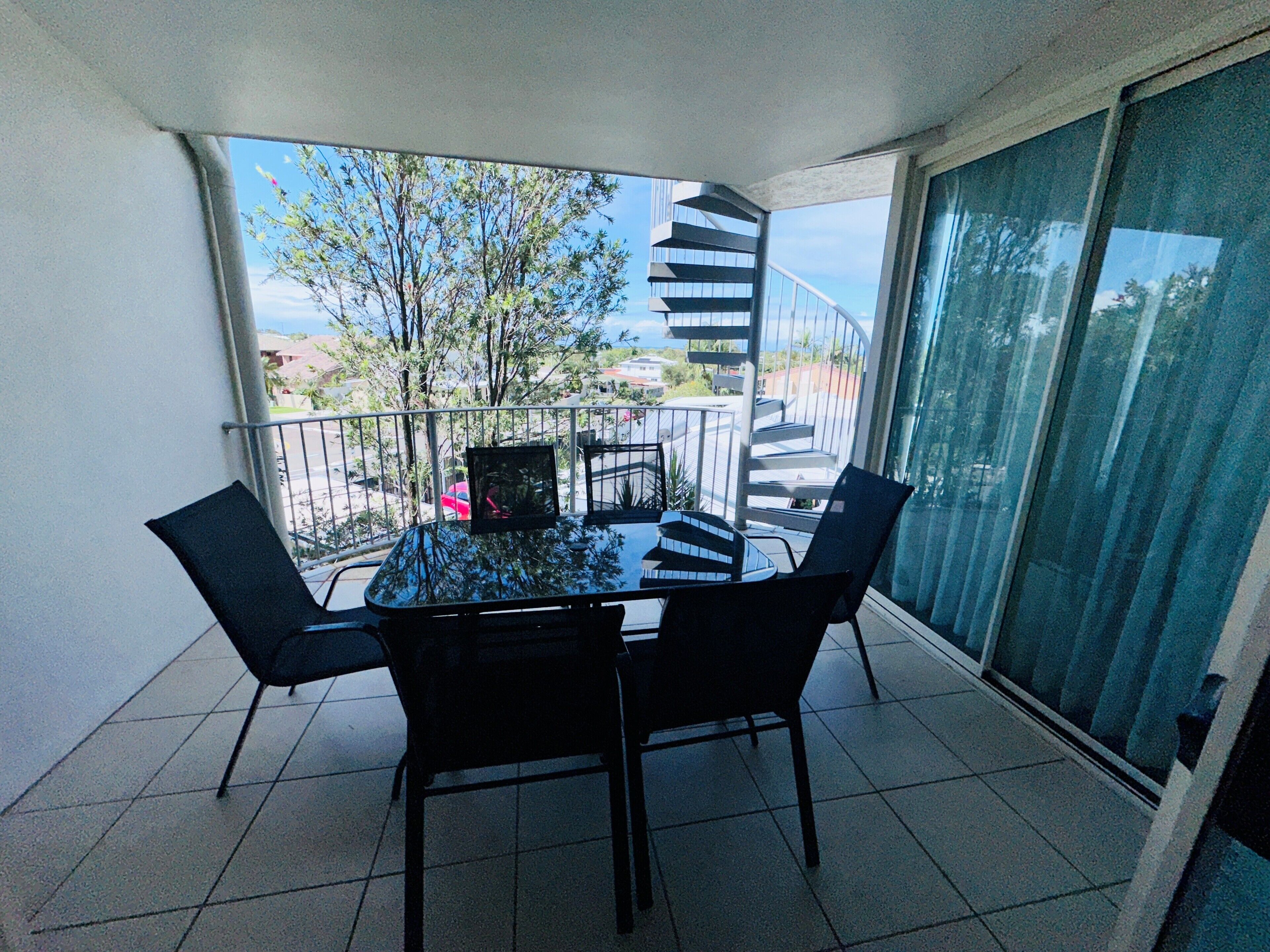 Un balcon avec une table et des chaises, un escalier en colimaçon et une vue sur les environs.