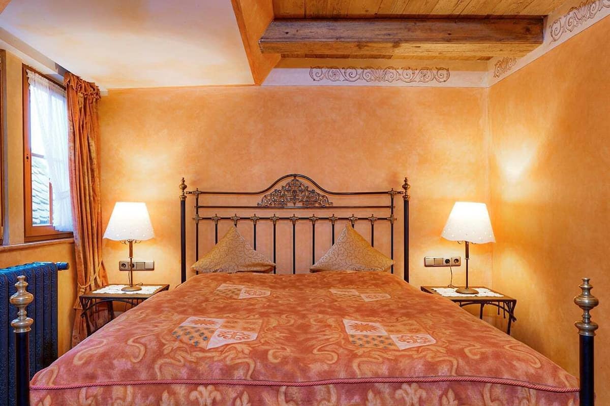 A bedroom with a large bed, two bedside tables, and a wooden ceiling.