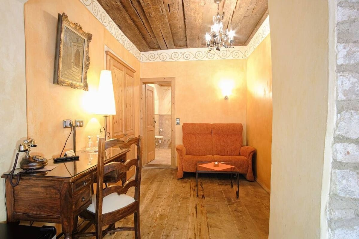 A room with a wooden desk, chair, and a sofa.