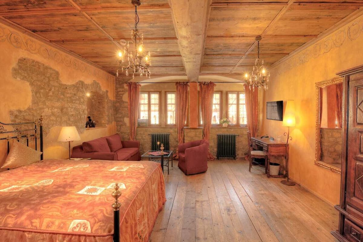 A traditional room with a large bed, a sofa, a chair, and a desk.