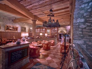 A cozy library with wooden bookshelves, a checkered floor, and a stone wall. - Hotel Gotisches Haus (Rothenburg ob der Tauber)