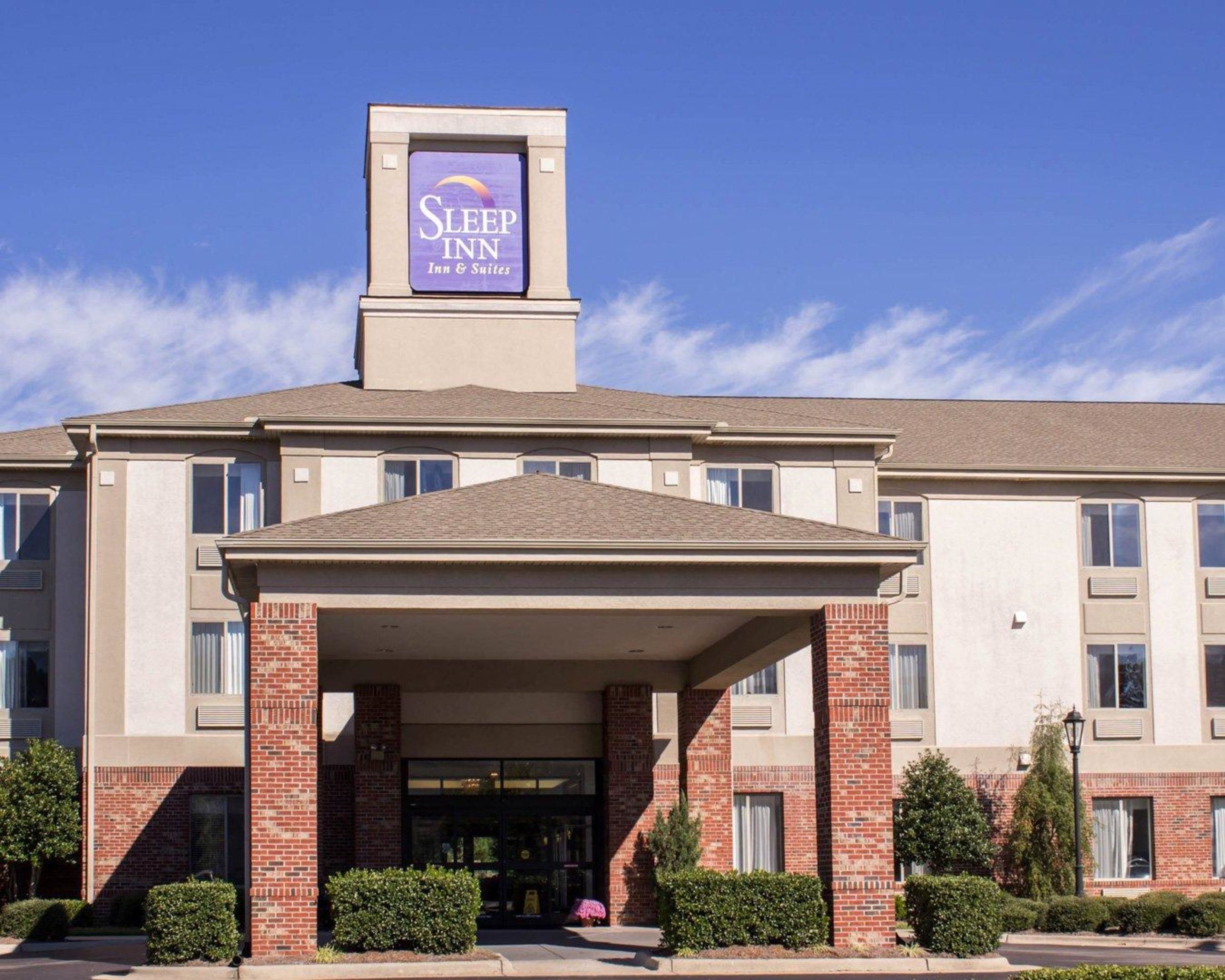A Sleep Inn & Suites building with a prominent entrance, brick columns, and a clear blue sky.