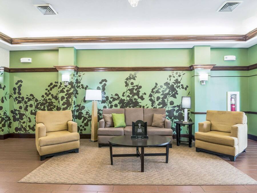 Un hall d’entrée avec deux fauteuils, un canapé, une table basse et un mur décoré de motifs.
