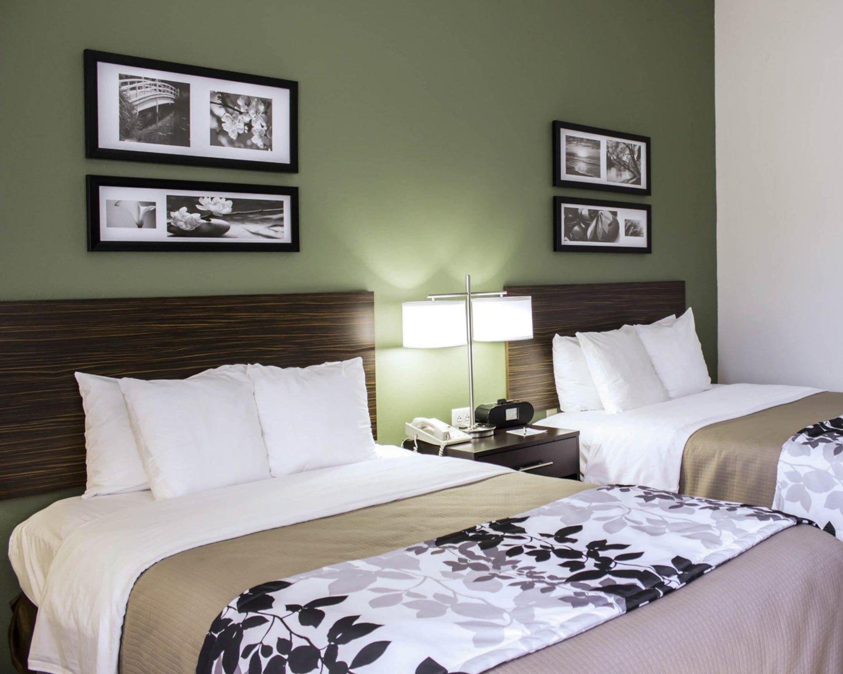 A hotel room with two beds, a nightstand with a lamp, and framed pictures on the wall.