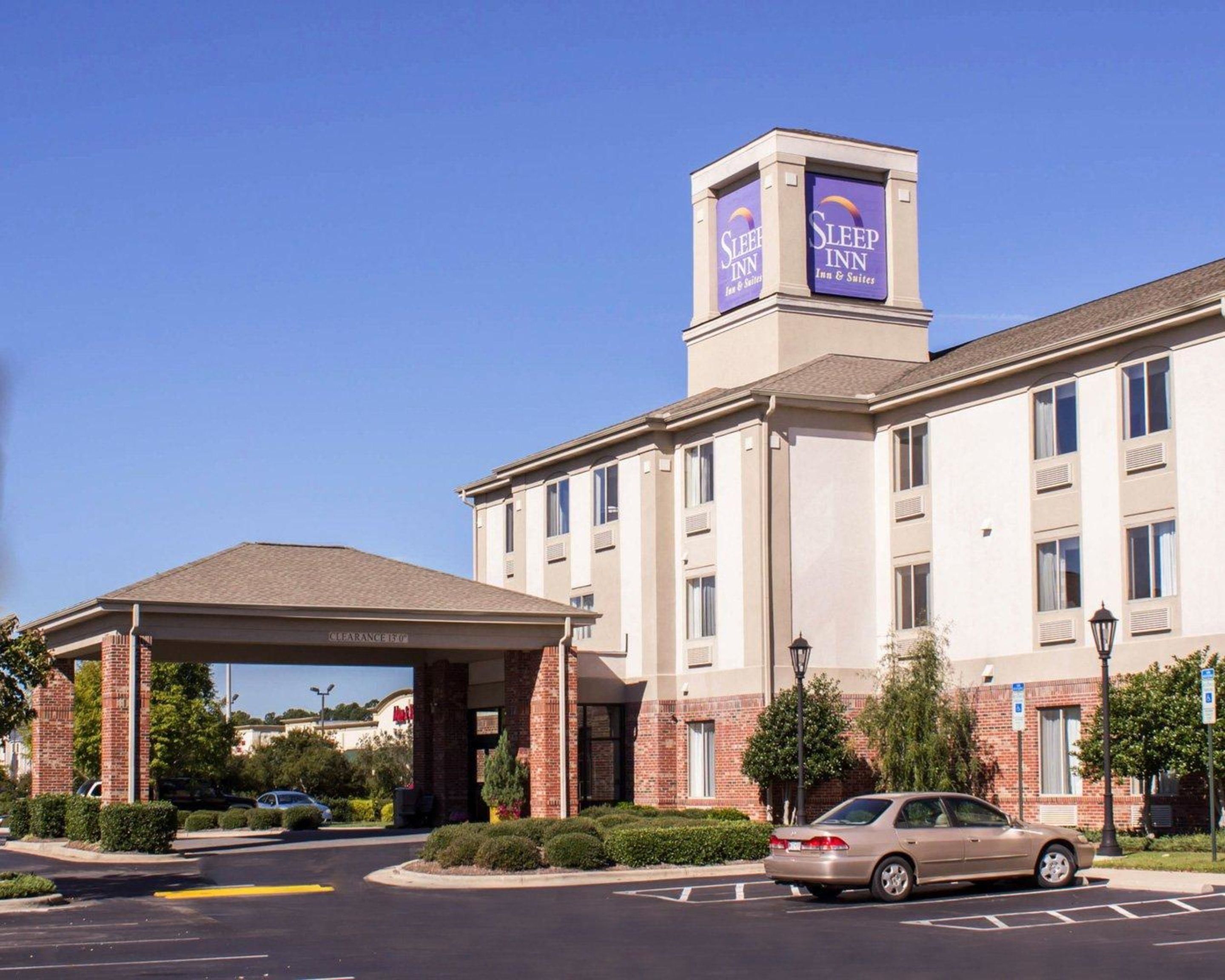 A Sleep Inn hotel with a clear entrance, parking lot, and a car parked in front.