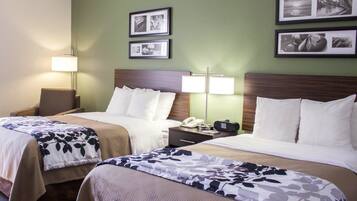 Une chambre d’hôtel avec deux lits, une table de chevet avec un téléphone et une radio, et des lampes fixées au mur.