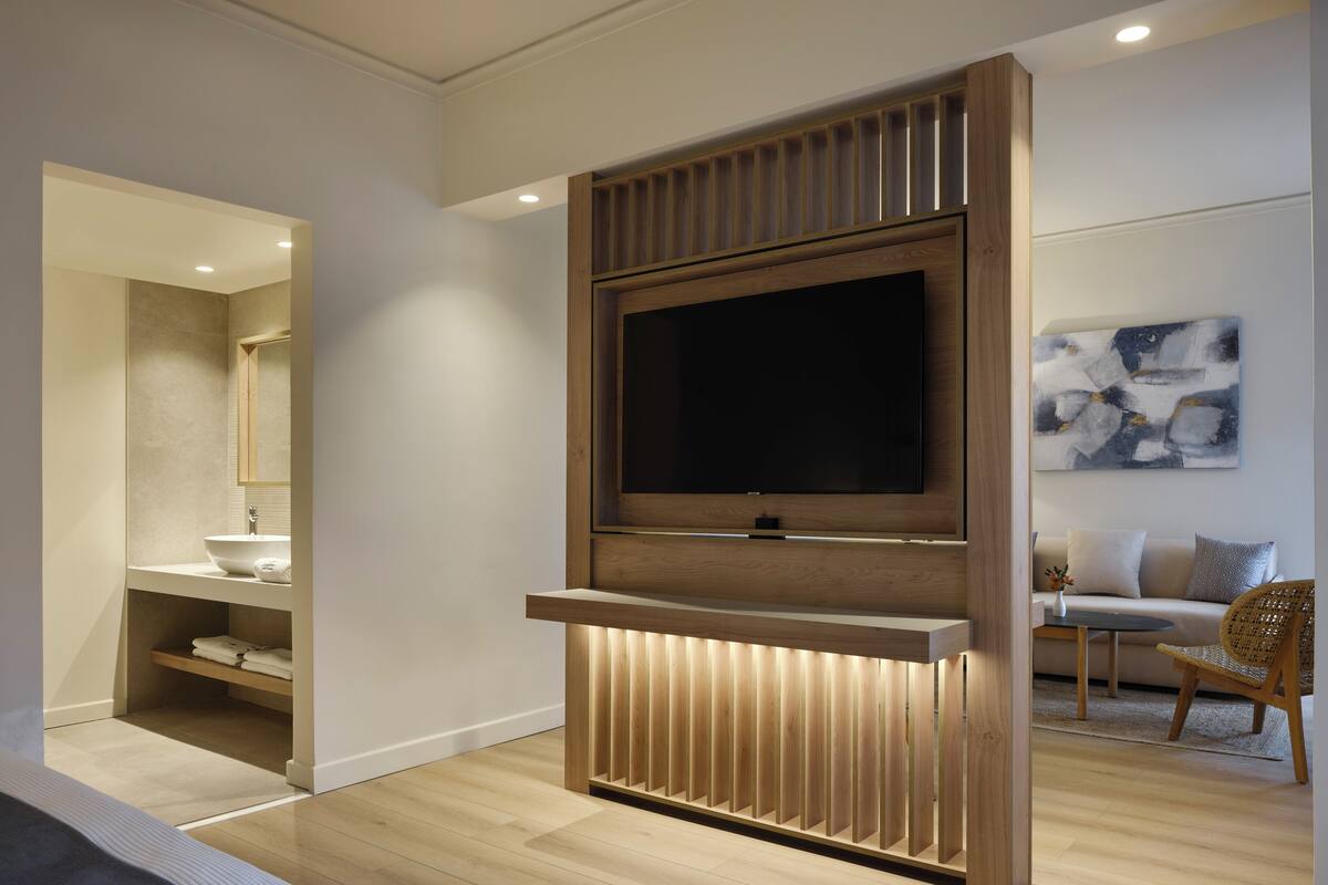 Un salon moderne avec un téléviseur à écran plat fixé sur un panneau en bois, un canapé et une table basse.