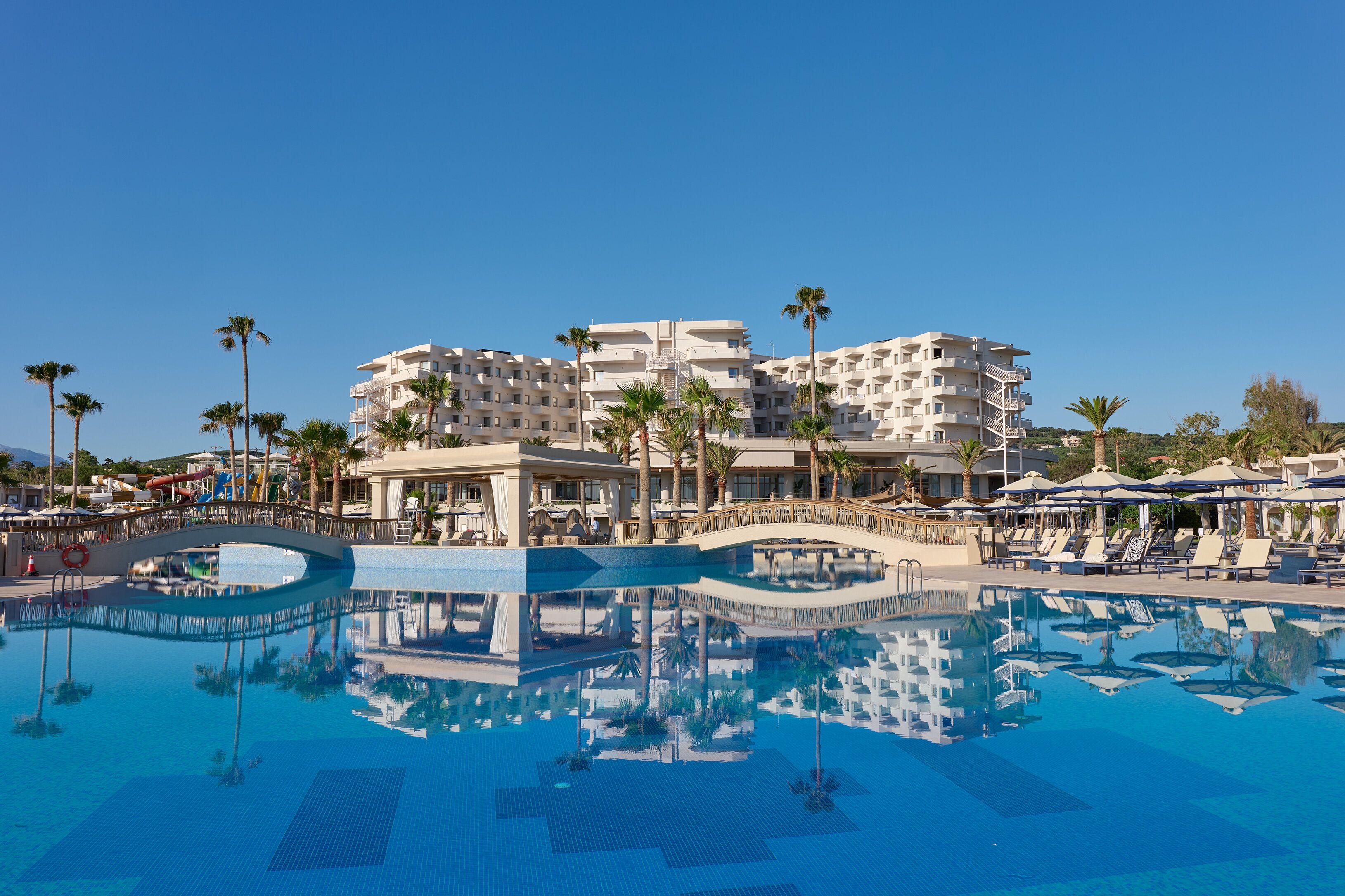 A resort with a large pool, palm trees, and modern buildings.