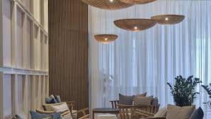 A modern interior with wooden furniture, woven light fixtures, and sheer curtains.