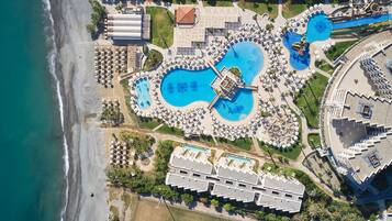 Eine Vogelperspektive zeigt einen luxuriösen Kurort mit mehreren Schwimmbecken, Zugang zum Strand und den dazugehörigen Gebäuden.