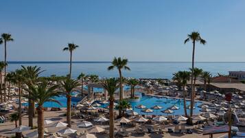 Ein Resort mit mehreren Schwimmbecken, Palmen und Liegestühlen.