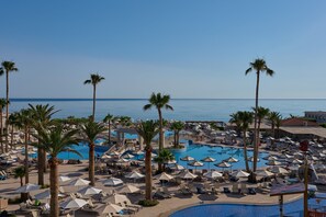 Un resort con varias piscinas, palmeras y tumbonas.