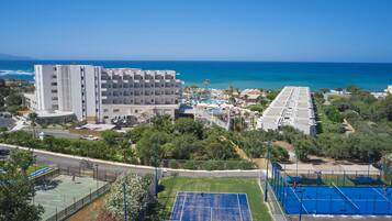 Un hotel frente al mar con cancha de tenis, piscina y vistas al océano.