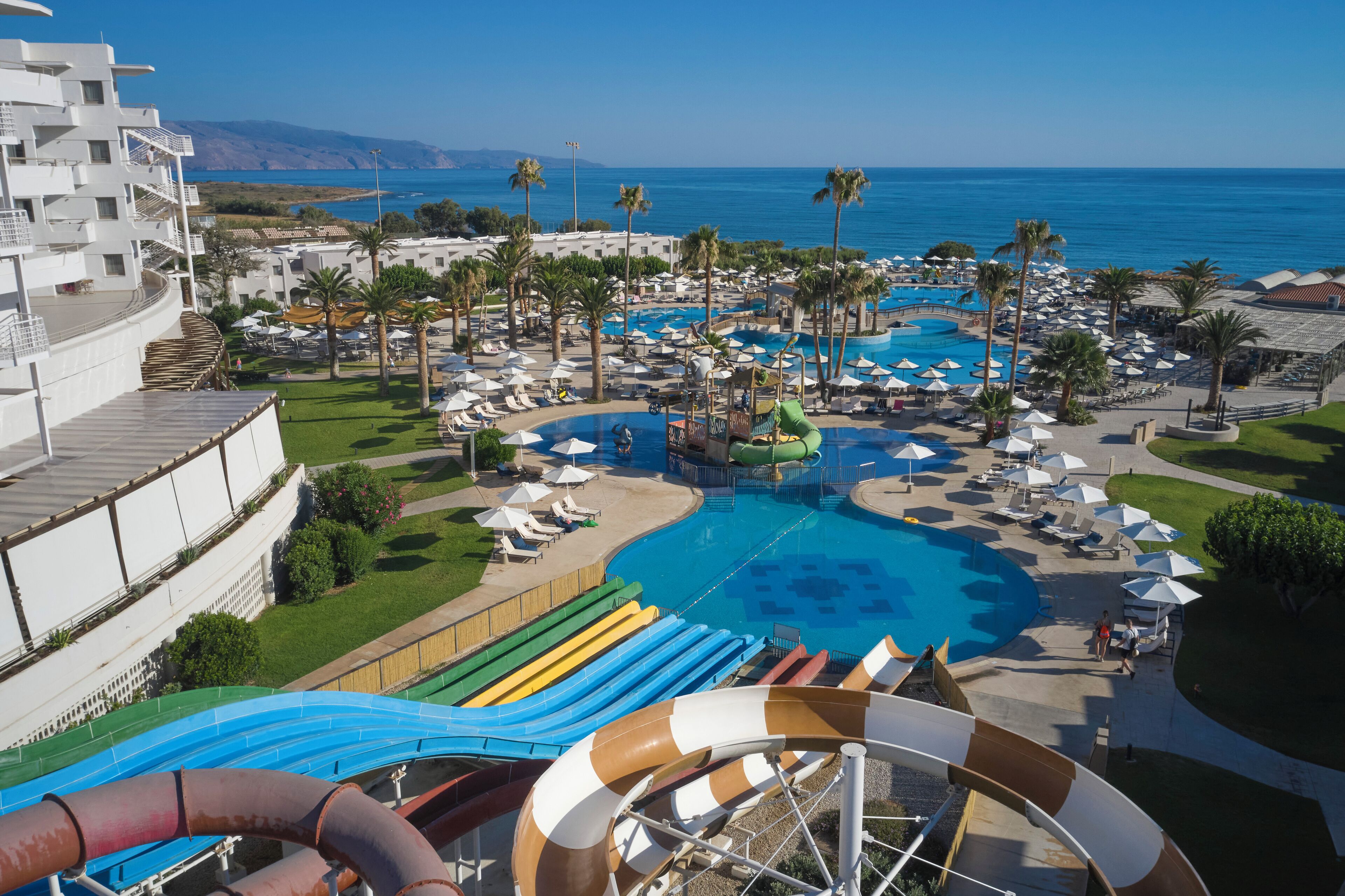A resort with a large pool, water slides, and palm trees.