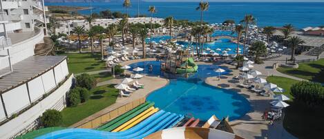 A resort with a large pool, water slides, and palm trees.