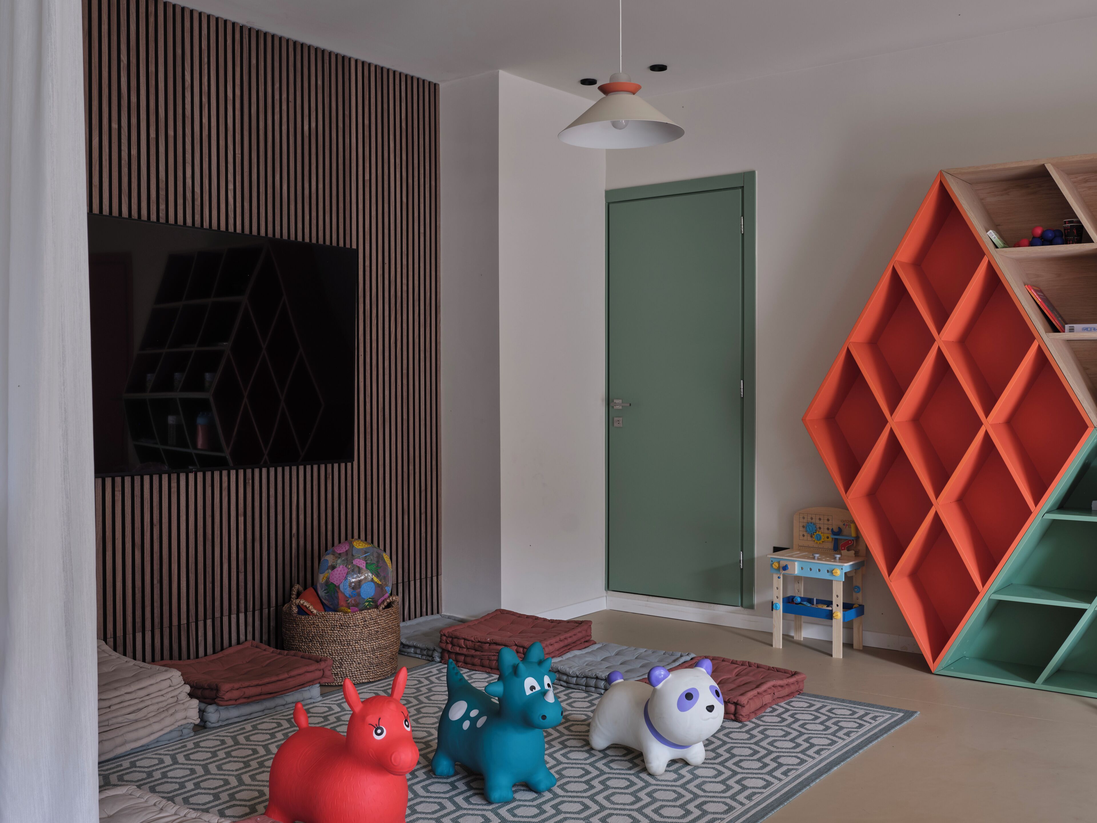A modern living room with a television, a green door, and a colorful storage unit.