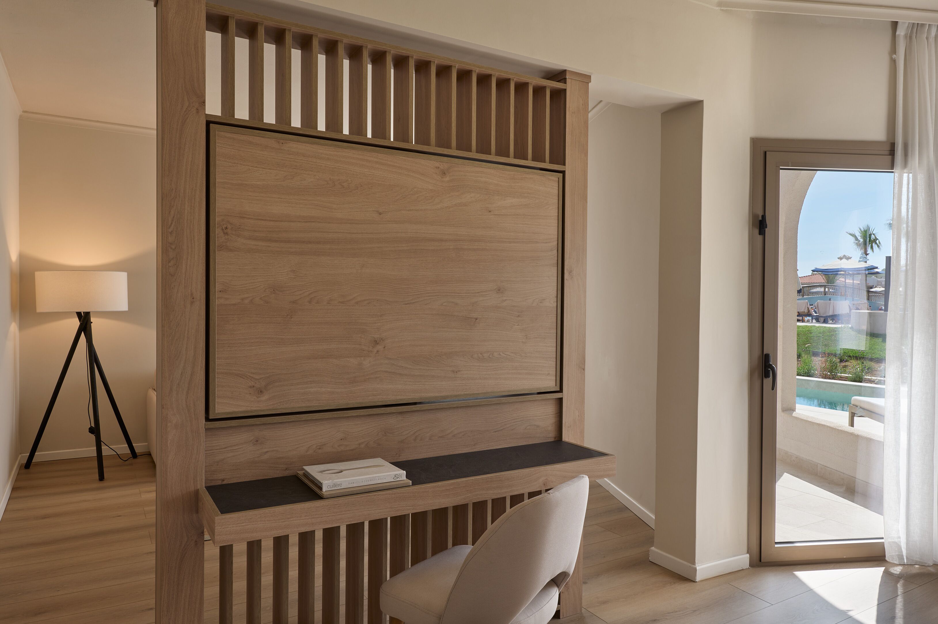 A modern room with a wooden desk, a chair, and a large TV.