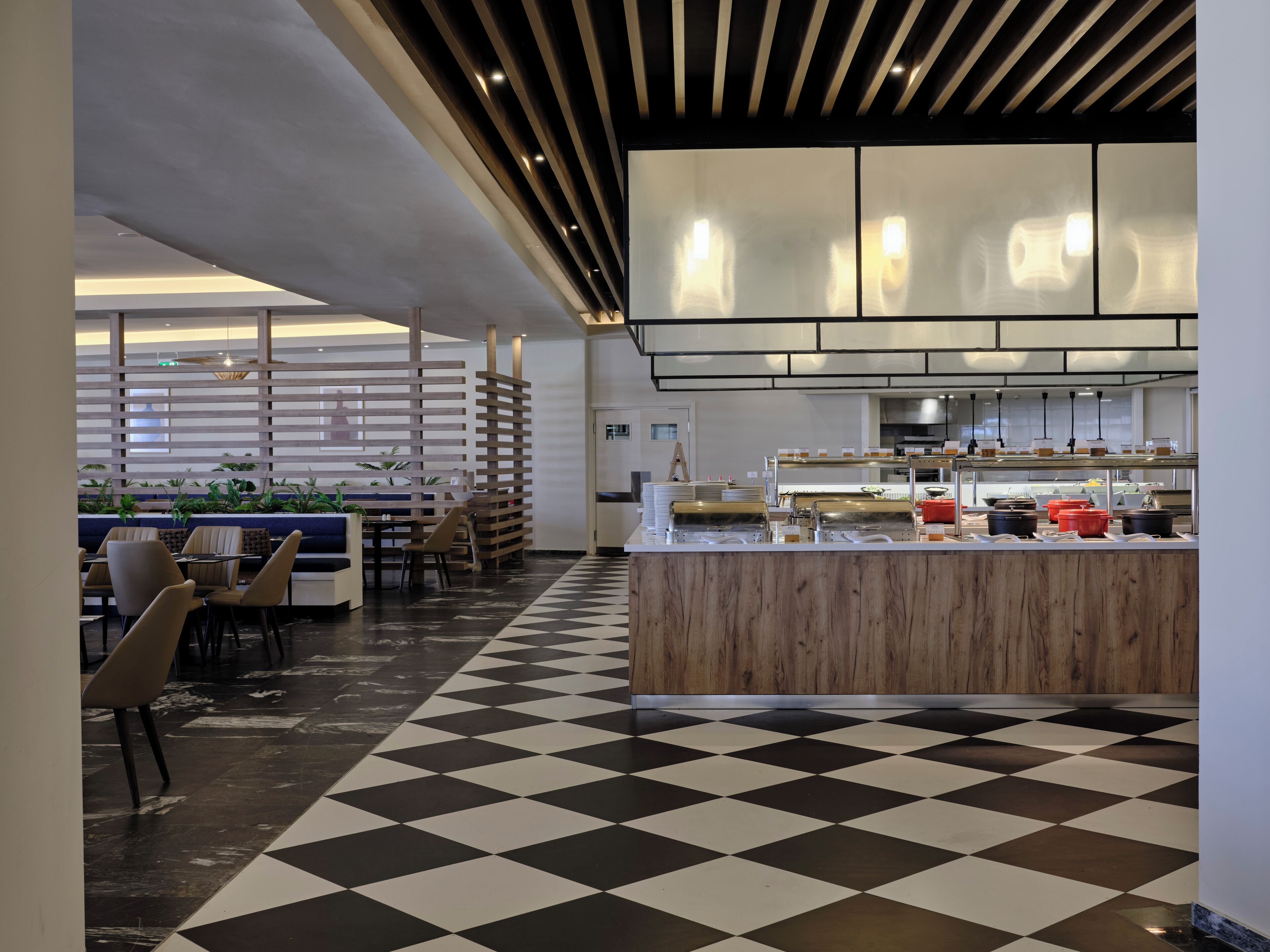 Un restaurante moderno con suelo a cuadros, muebles de madera y una zona de cocina con diverso equipo.