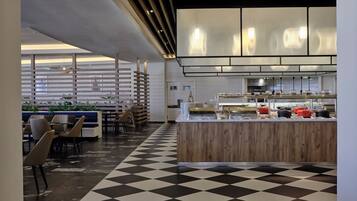 Un restaurante moderno con suelo a cuadros, muebles de madera y una zona de cocina con diverso equipo.