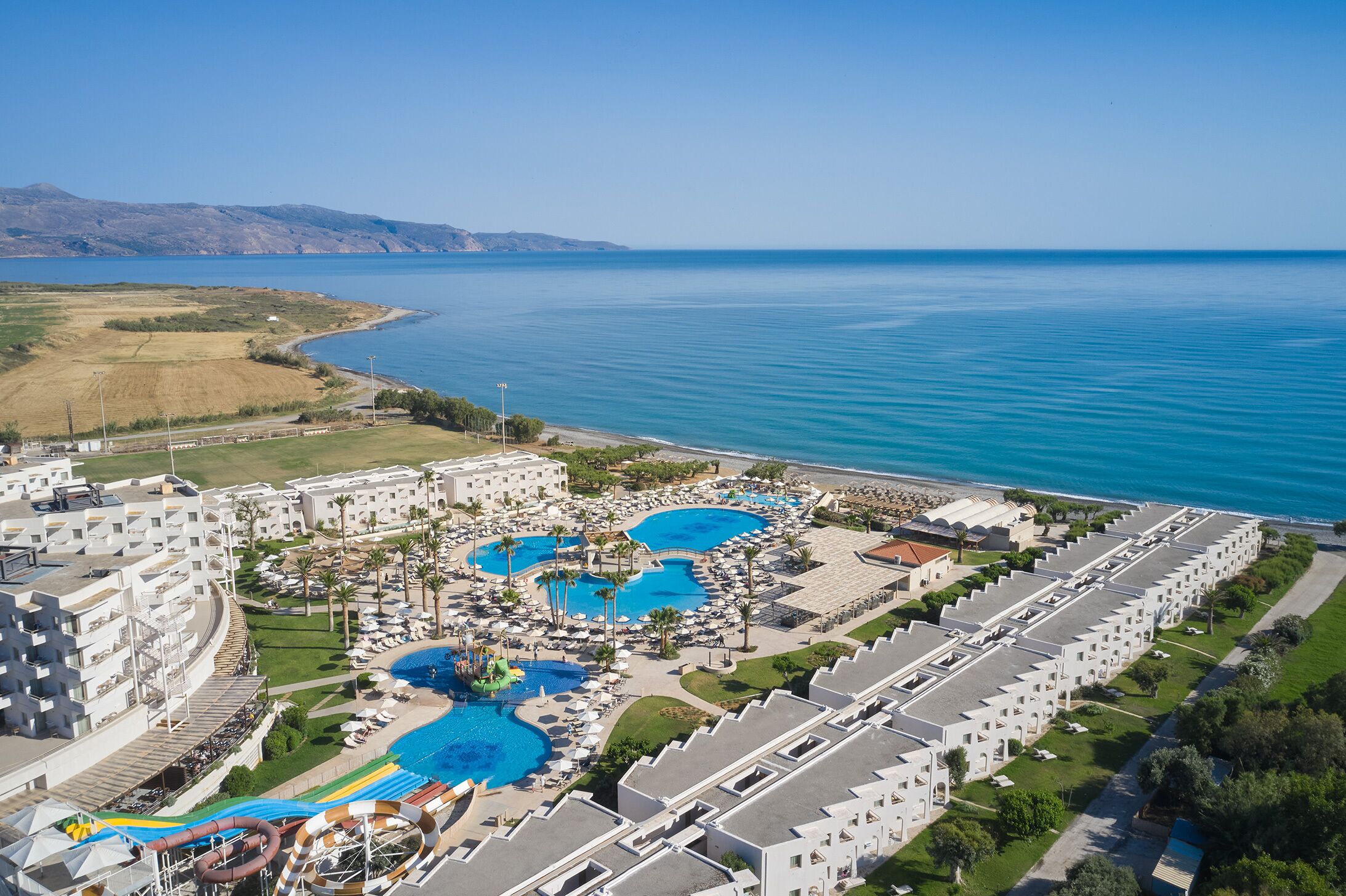 Ein Resort mit mehreren Schwimmbecken, einer Wasserrutsche und Meerblick.
