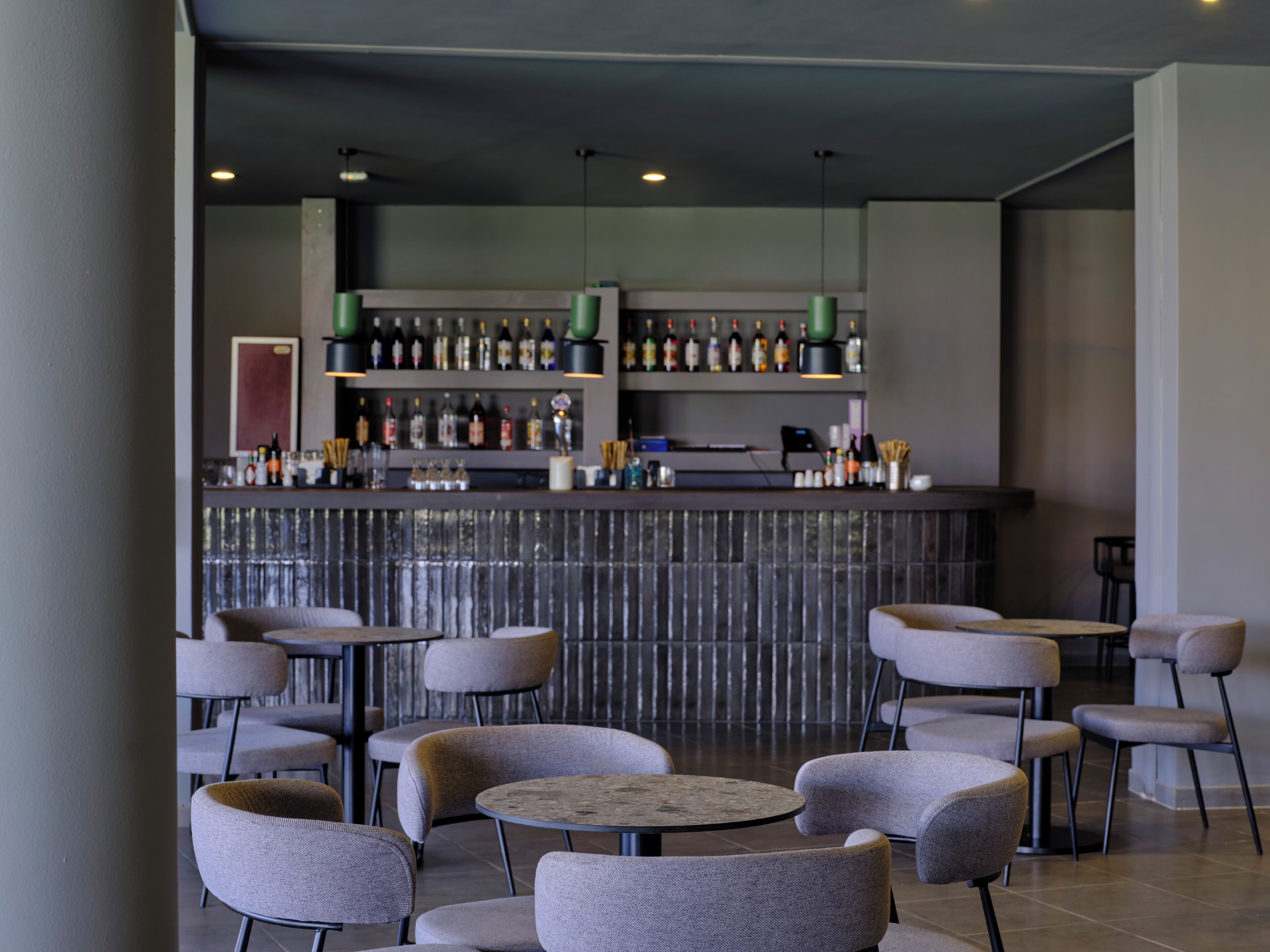 Un espace bar moderne offrant différents types de sièges et un comptoir bien garni.