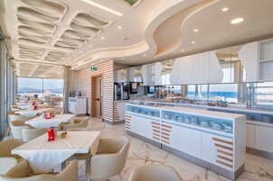 Un restaurante moderno con mostrador central, zona de estar y vistas al mar.