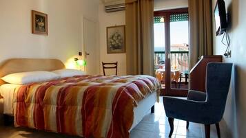 Een hotelkamer met een bed, een stoel, een televisie en een balkon met een tafel en stoelen.