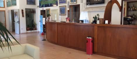 A lobby with a reception desk, seating area, and artwork on the walls.