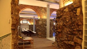 Un espace spa avec des murs en pierre, un plancher en bois et un coin salon comprenant une table et des chaises.