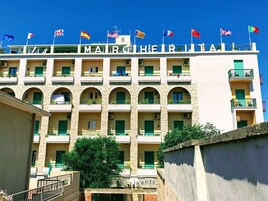 A hotel with multiple balconies, arched windows, and flags from various countries.