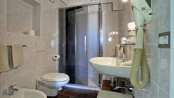 Un baño moderno con inodoro, bidé, lavabo y cabina de ducha con mampara de vidrio.