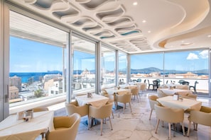 Un restaurante moderno con amplios ventanales que ofrecen vista a la ciudad.