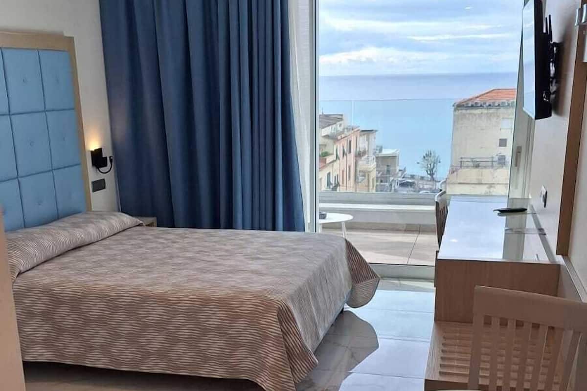Una habitación de hotel con cama, una mesa de comedor y vista al mar.