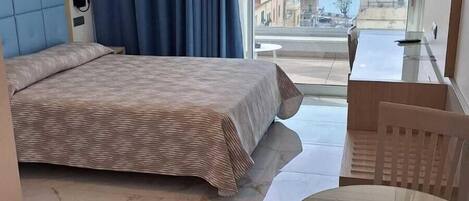 Quarto de hotel com cama, mesa de jantar e vista para o mar.