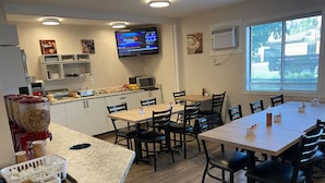 A modern kitchen with a dining area, equipped with a TV, air conditioning, and various kitchen appliances. - Dilworth Inn (Kelowna)
