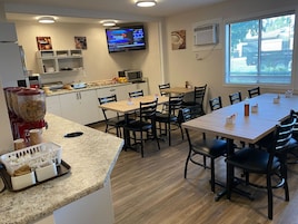 A modern kitchen with a dining area, equipped with a TV, air conditioning, and various kitchen appliances.