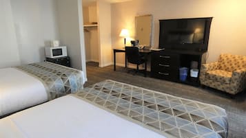 Una habitación de hotel con dos camas, un escritorio con computadora, un televisor y una silla.