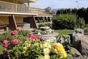A building with a balcony, outdoor seating, and a garden with flowers and rocks.